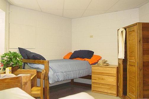 Keystone College dorm room with bed and wooden furniture